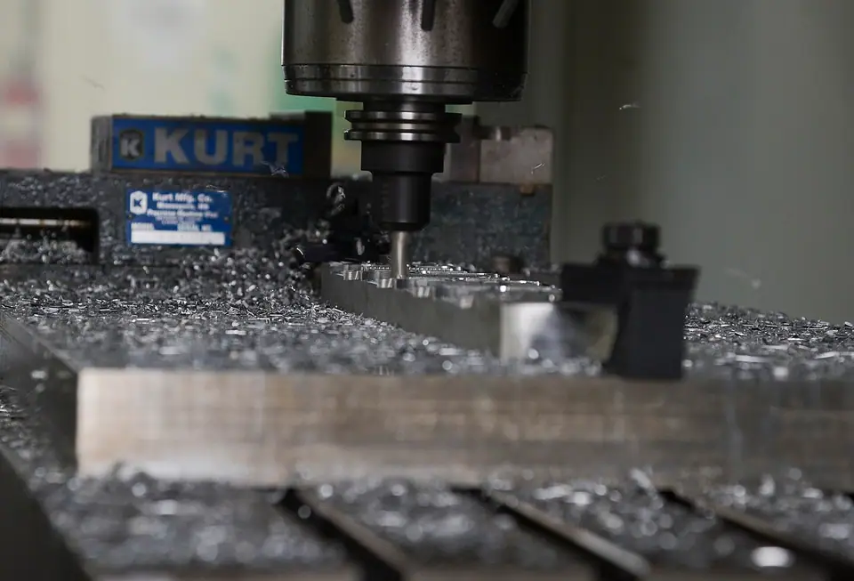 CNC freze tezgâhında işlenen metal blok ve etrafındaki talaşlar