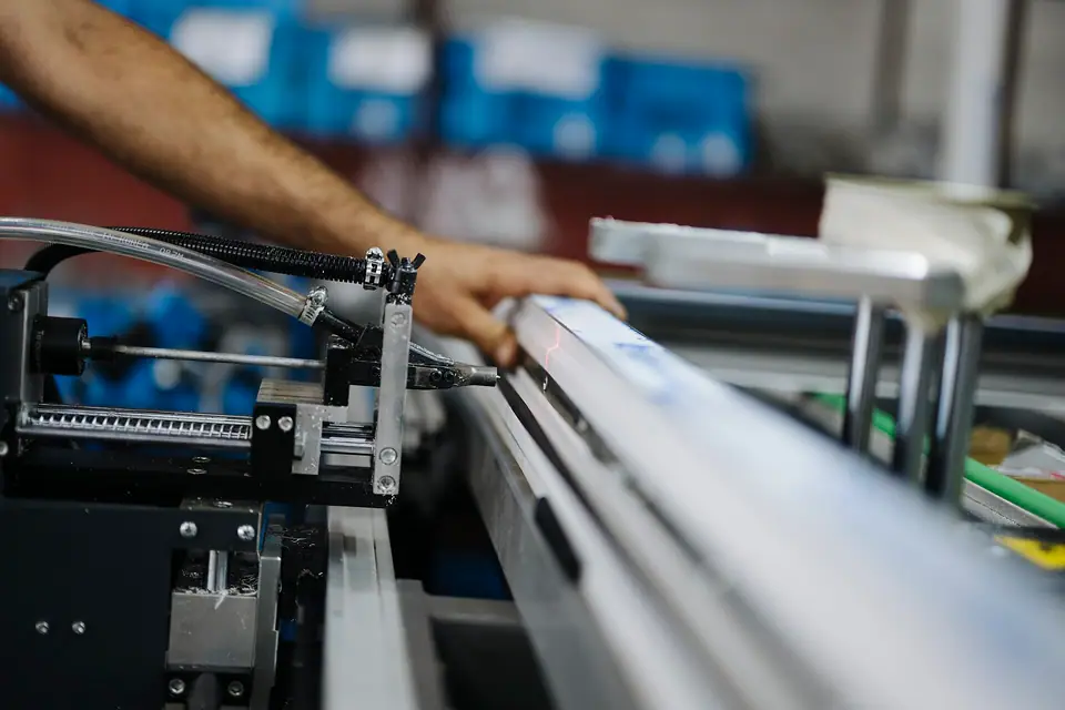 Fabrikada bir makinenin başında parça yerleştiren eller