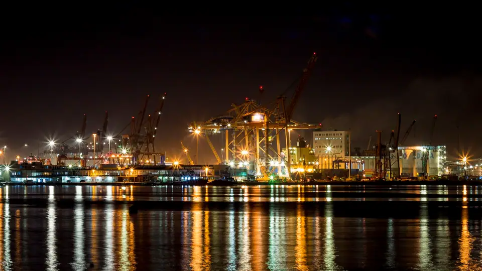 Gece ışıklar içindeki Mersin Limanı'nın vinçleri ve suya yansıyan ışıklar